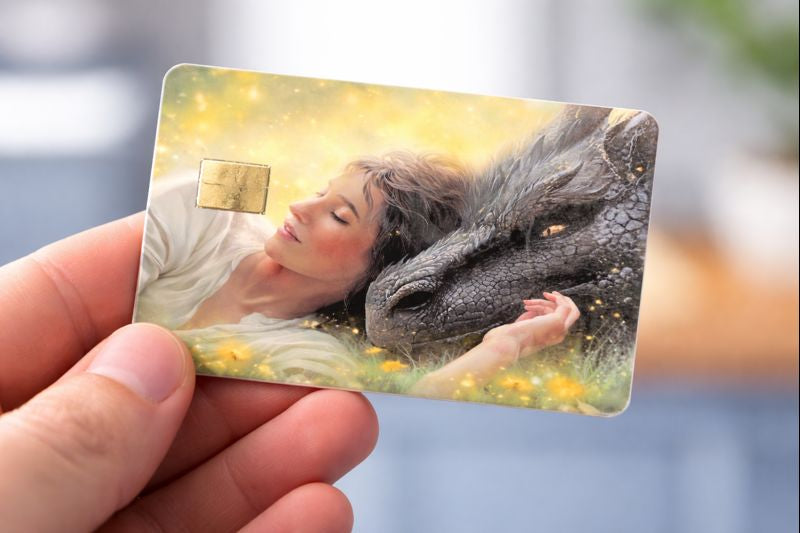 Soft fantasy illustration of a girl sleeping beside a large dragon printed on durable vinyl card skin."