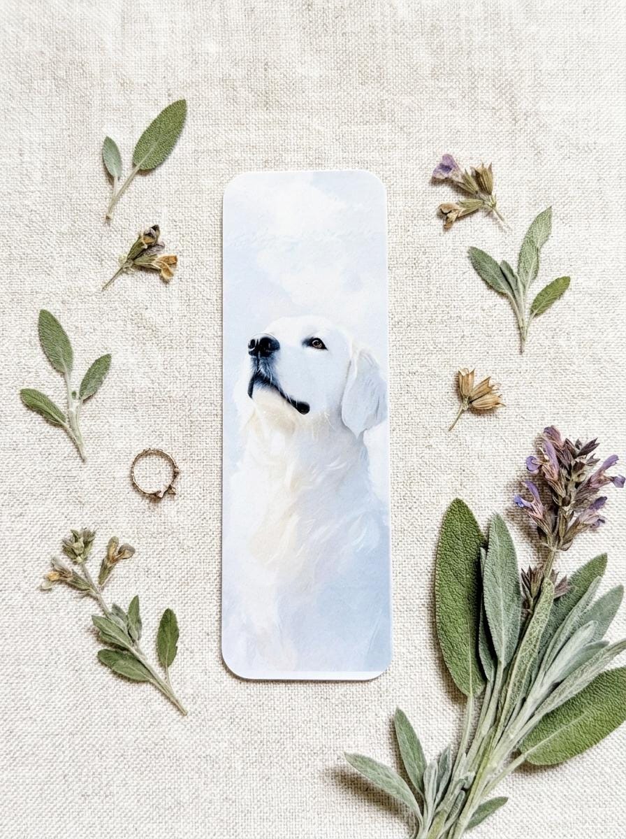 Close-up of a single English Cream Golden Retriever watercolor bookmark on a beige linen background, surrounded by sage leaves, dried flowers, and lavender. __etsy:8181674245