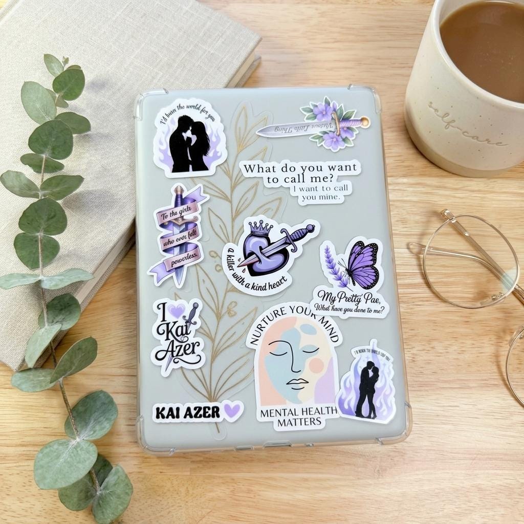 A clear white Kindle e-reader covered in book boyfriend vinyl stickers, resting on a wooden table with a eucalyptus sprig, a cream self-care mug, and reading glasses. Decals include Nurture Your Mind, Mental Health Matters, a serene face illustration, a purple butterfly, couple silhouettes, and the name Kai Azer. __etsy:8181761451
