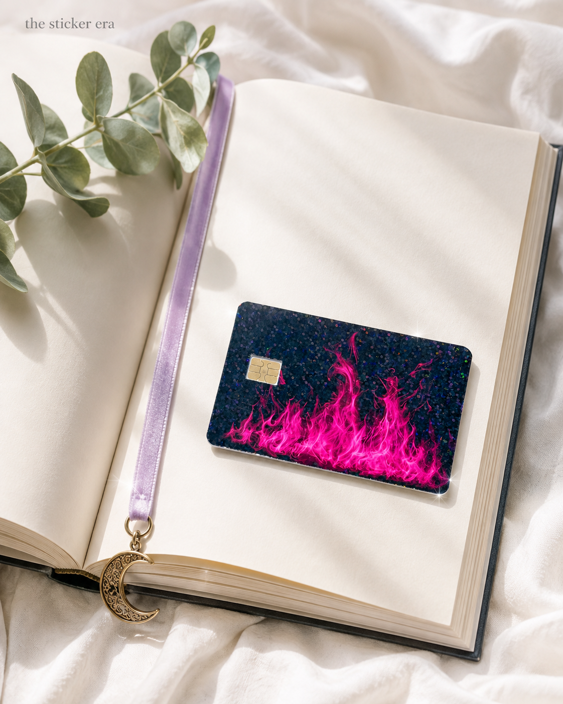 Hot pink flame debit card skin resting on an open journal with greenery by The Sticker Era