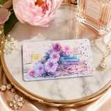 Pastel floral book card skin on a gold tray with a pink peony, pearls and a perfume bottle on blush satin by The Sticker Era
