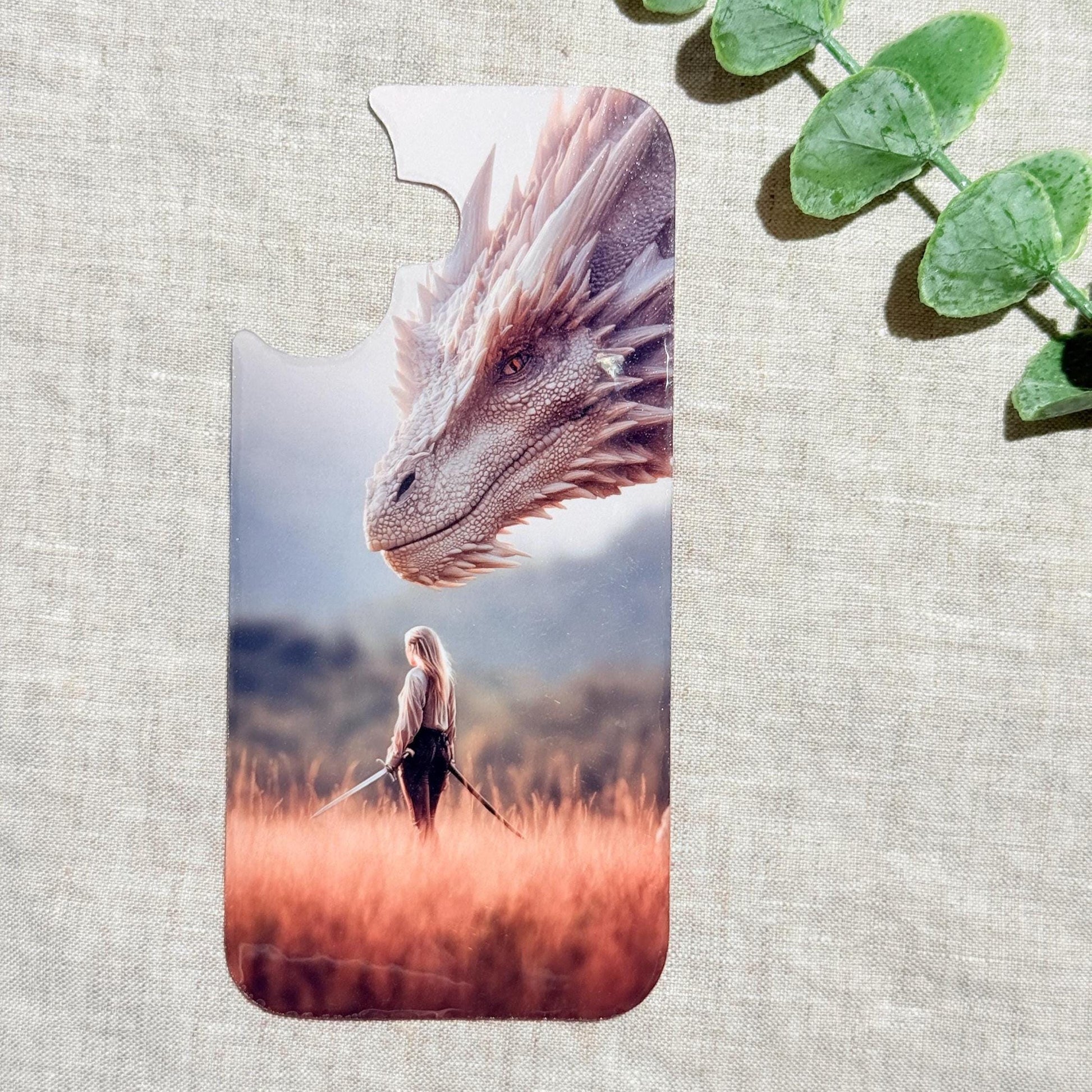 Dragon and rider phone insert. a silver dragon's head above a woman holding a sword in a golden grass field, shown on a linen background with eucalyptus sprigs. __etsy:8118197670