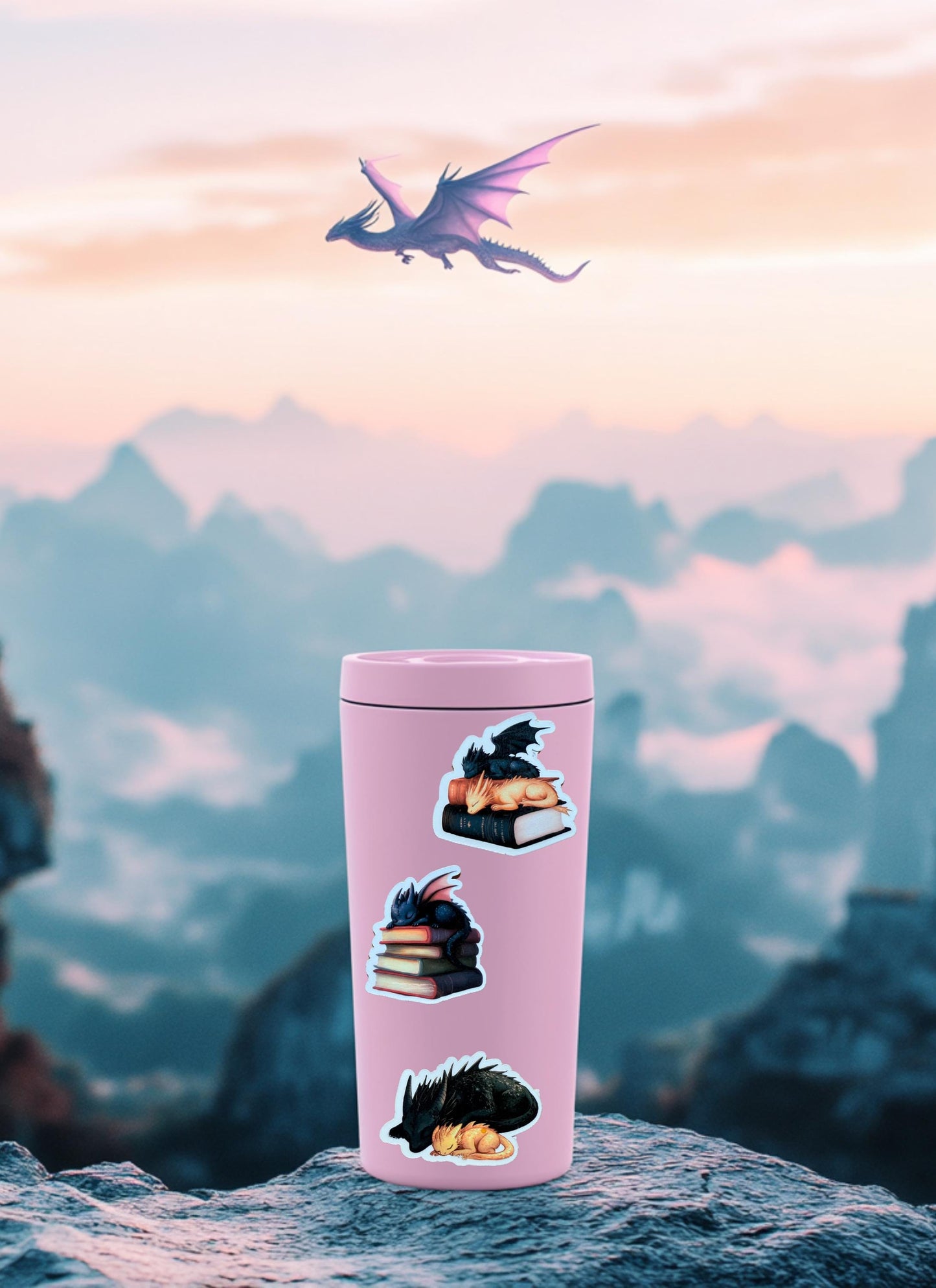 May include: A pink travel mug with three black and gold dragon stickers. The stickers depict dragons sleeping on staPink tumbler displaying three book dragon stickers, set against a dreamy pastel mountain landscape with a purple dragon soaring through the sunset sky.cks of books. The mug is sitting on a rock with a mountain range and a pink sky in the background. __etsy:6823102315