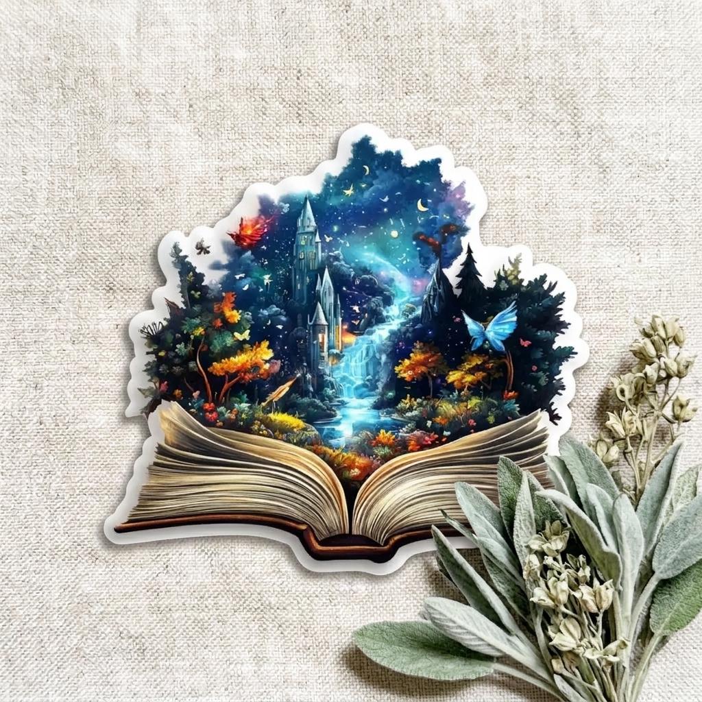 Die-cut vinyl sticker of a fantasy castle and magical forest rising from an open book, with a starry night sky, glowing blue waterfall, autumn trees, and a blue butterfly, shown on a linen background with dried sage. __etsy:8133849108
