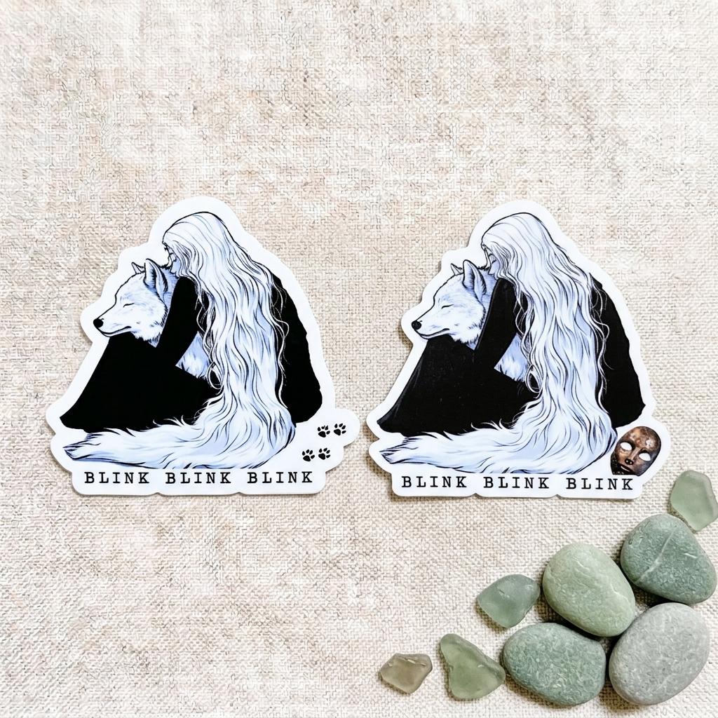 Two die-cut vinyl stickers of a fantasy wolf girl with long flowing white hair embracing a white wolf, with the words BLINK BLINK BLINK at the bottom, shown on a natural linen background with smooth green and gray stones. __etsy:8182208893