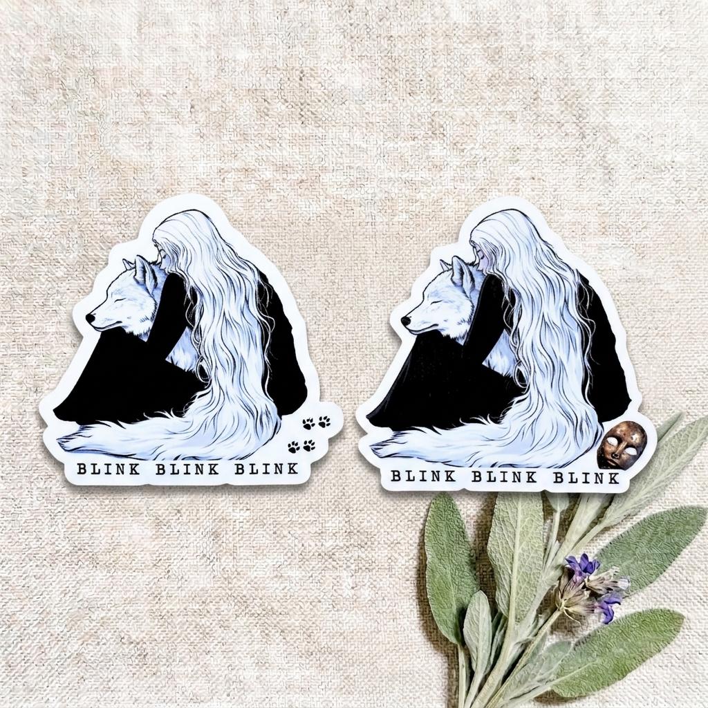 Two fantasy wolf girl die-cut stickers of a long-haired girl embracing a white wolf with BLINK BLINK BLINK text, shown on a natural linen background with a sprig of sage leaves and small purple flowers. __etsy:8182208891