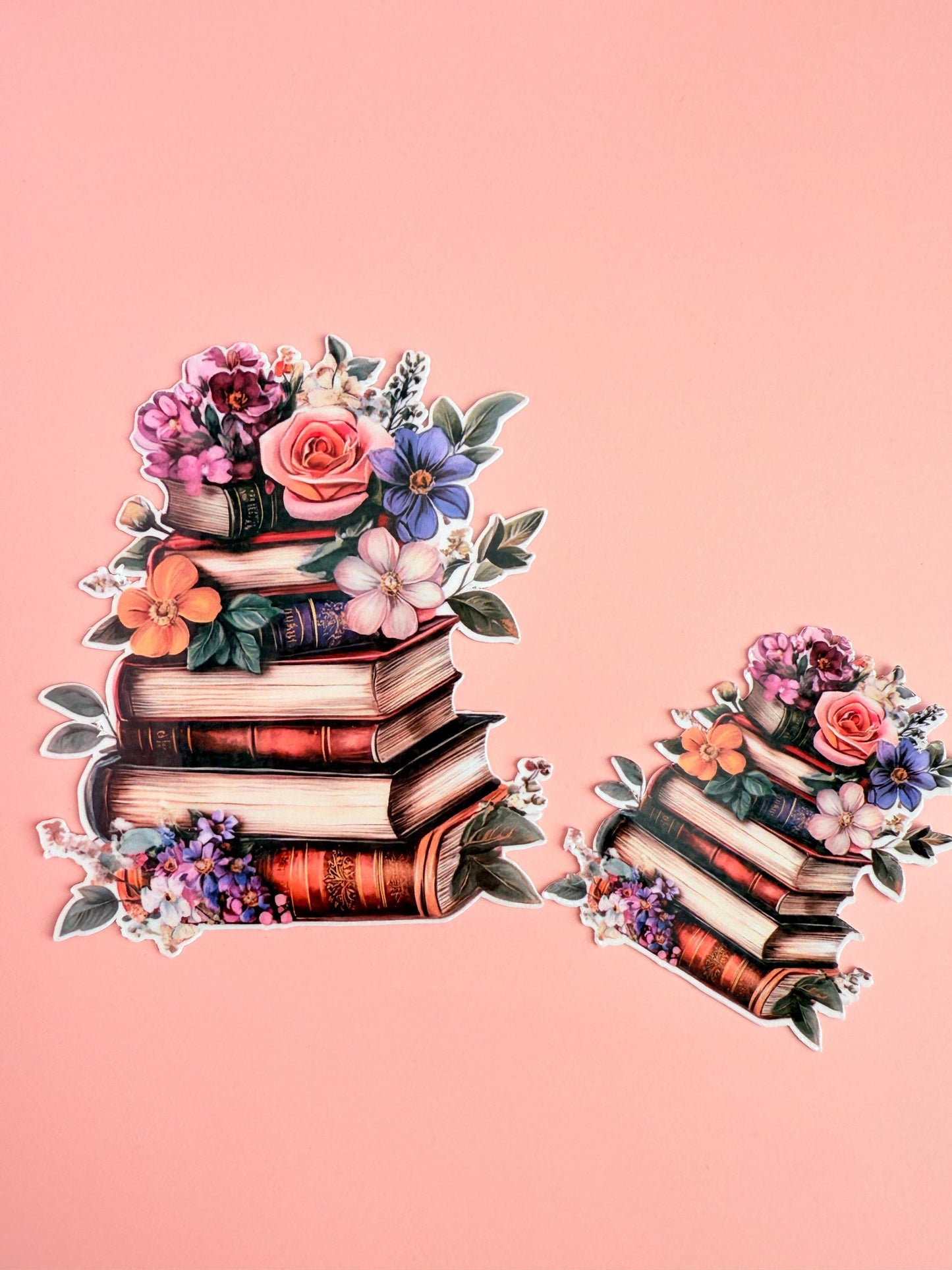 A vinyl sticker featuring a stack of vintage books adorned with colorful flowers and green leaves, placed on a soft pink background __etsy:6960137191