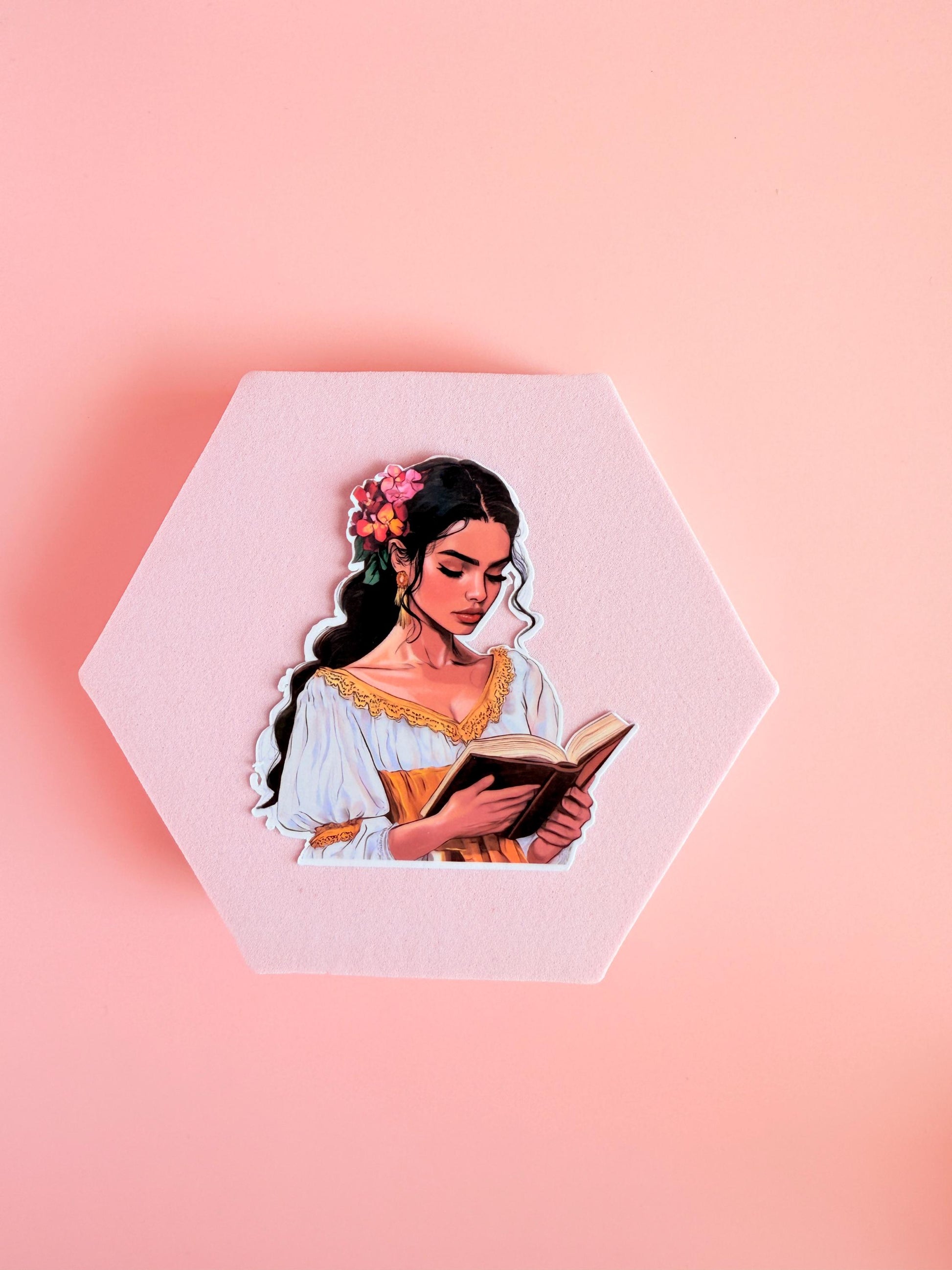Woman with black hair and flowers, wearing a white and gold dress, reading a book. Bright bookish sticker on a pink background. __etsy:6893048368