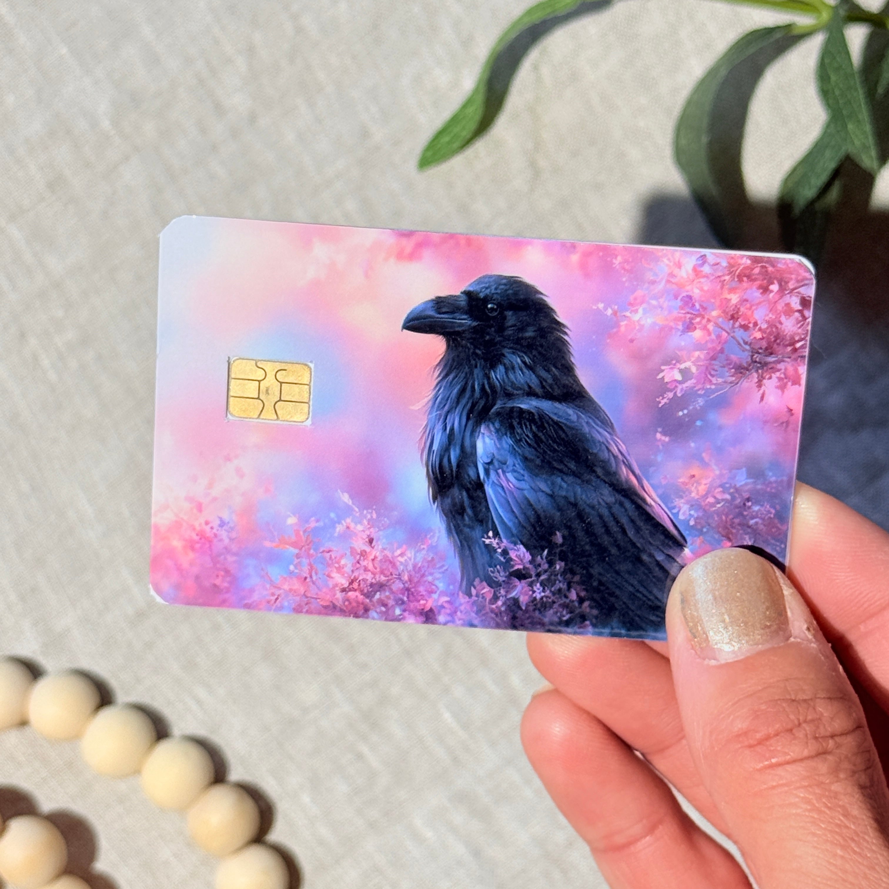Hand holding a raven cherry blossom debit card skin in natural light by The Sticker Era