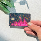 Hand holding a black and hot pink fire credit card skin with glitter by The Sticker Era
