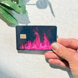 Hand holding a hot pink flame debit card skin in sunlight by The Sticker Era