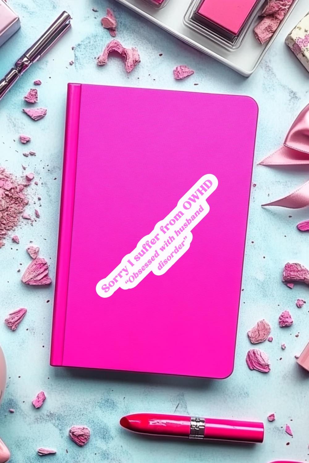 The "Sorry I suffer from OWHD - Obsessed with husband disorder" sticker applied diagonally to a hot pink journal. Styled as a glam flat-lay on a pale blue surface with crushed pink blush, a red lipstick, and a satin ribbon. __etsy:7771847154
