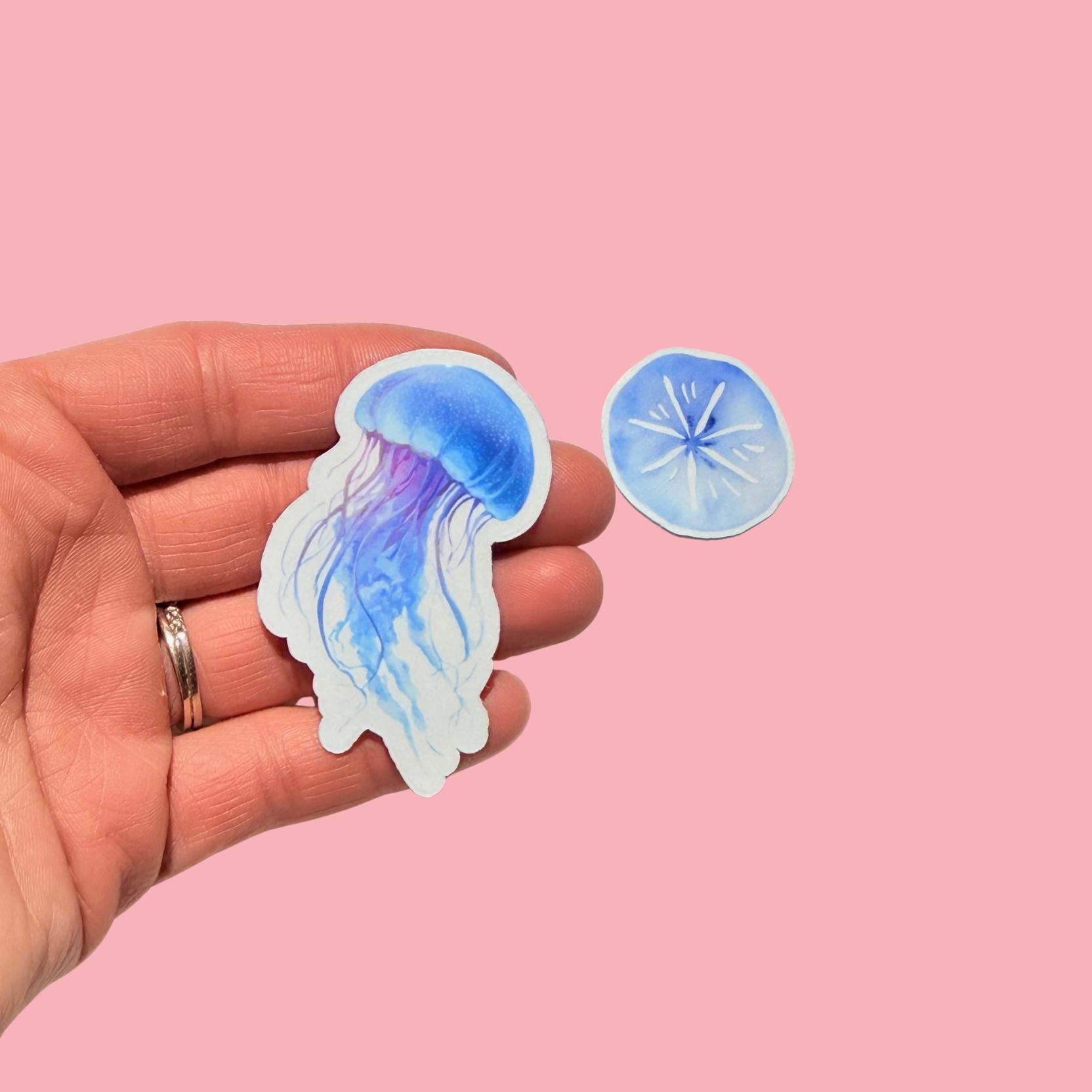 hand holding a lavender and blue jellyfish with a blue sand star in the background __etsy:7990815102