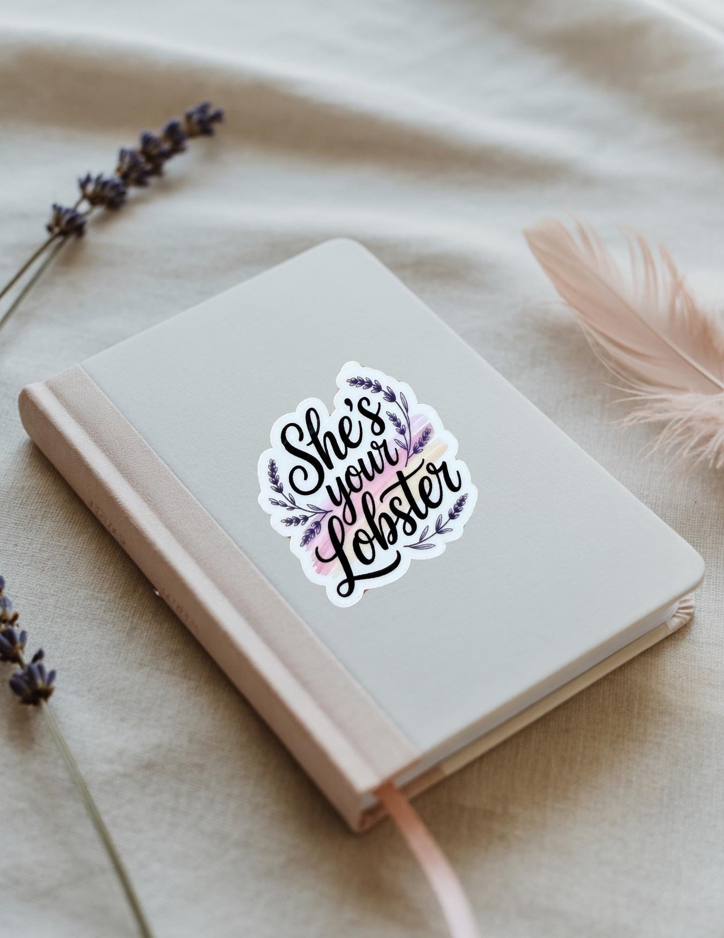 Vinyl sticker with the phrase “She’s Your Lobster” in black script surrounded by purple leaves, shown on a beige notebook. Inspired by the TV show Friends and perfect for romantic gifts or fans. __etsy:6853076034