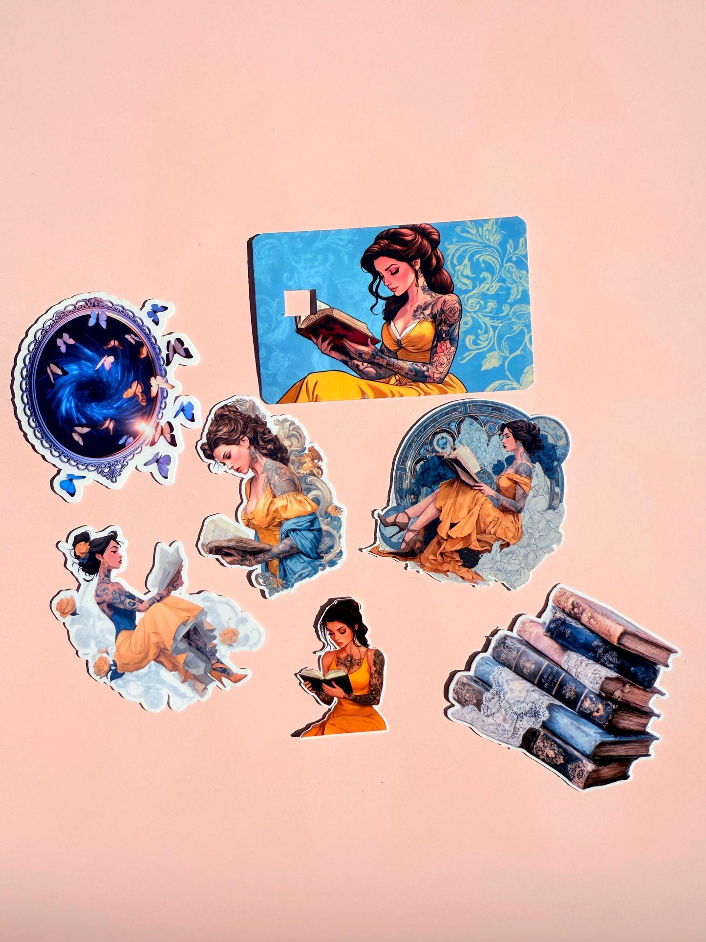Book lover sticker bundle arranged on a soft pink background, showing vinyl decals of tattooed women reading, a galaxy sticker, a stack of vintage books, and a blue debit card skin with a woman in a yellow dress reading. __etsy:6977166688