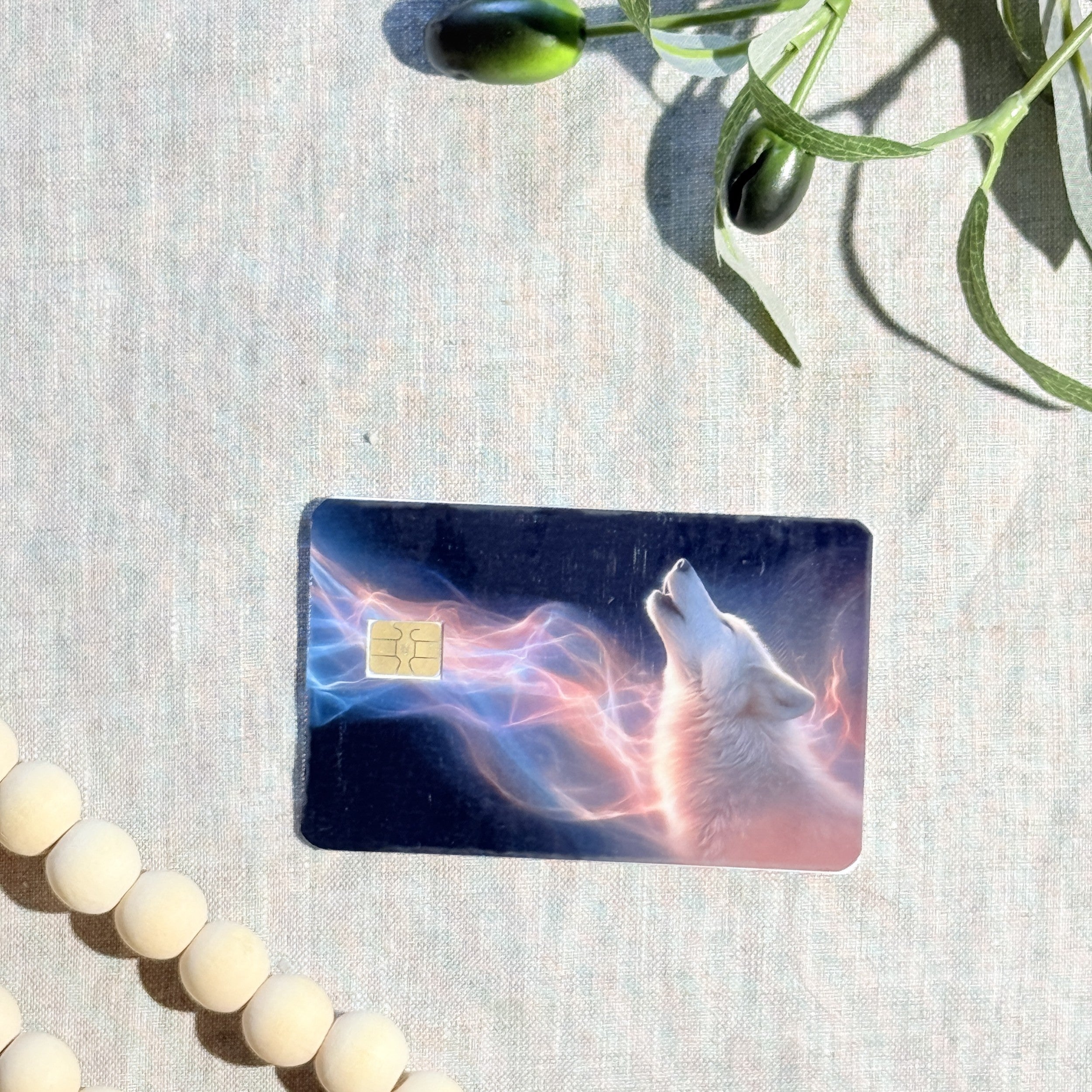 Aurora wolf card skin with white wolf howling into northern lights on a debit card by The Sticker Era
