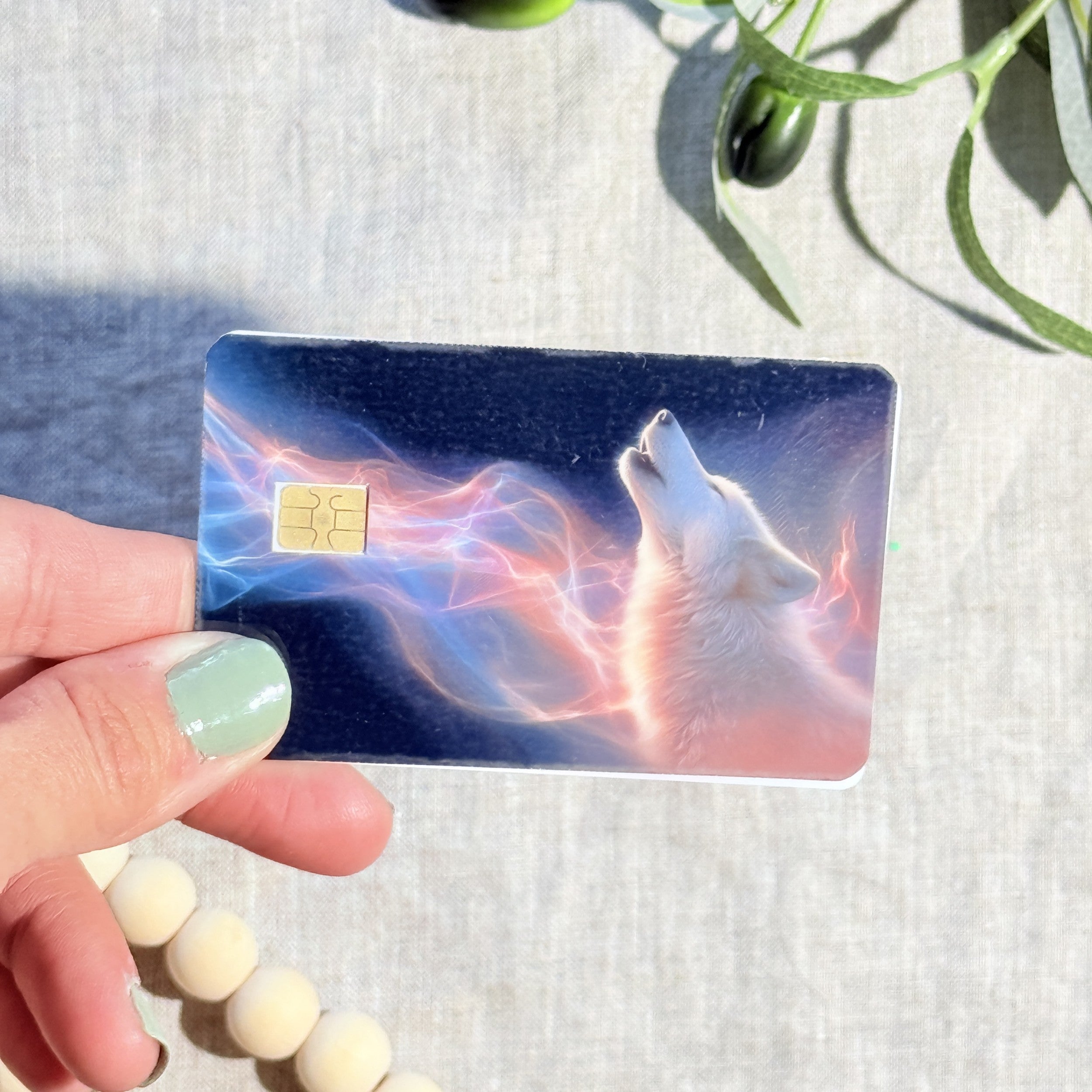 Aurora wolf debit card skin flat lay on cream linen by The Sticker Era