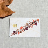Fall leaves and blade debit card sticker shown flat on linen