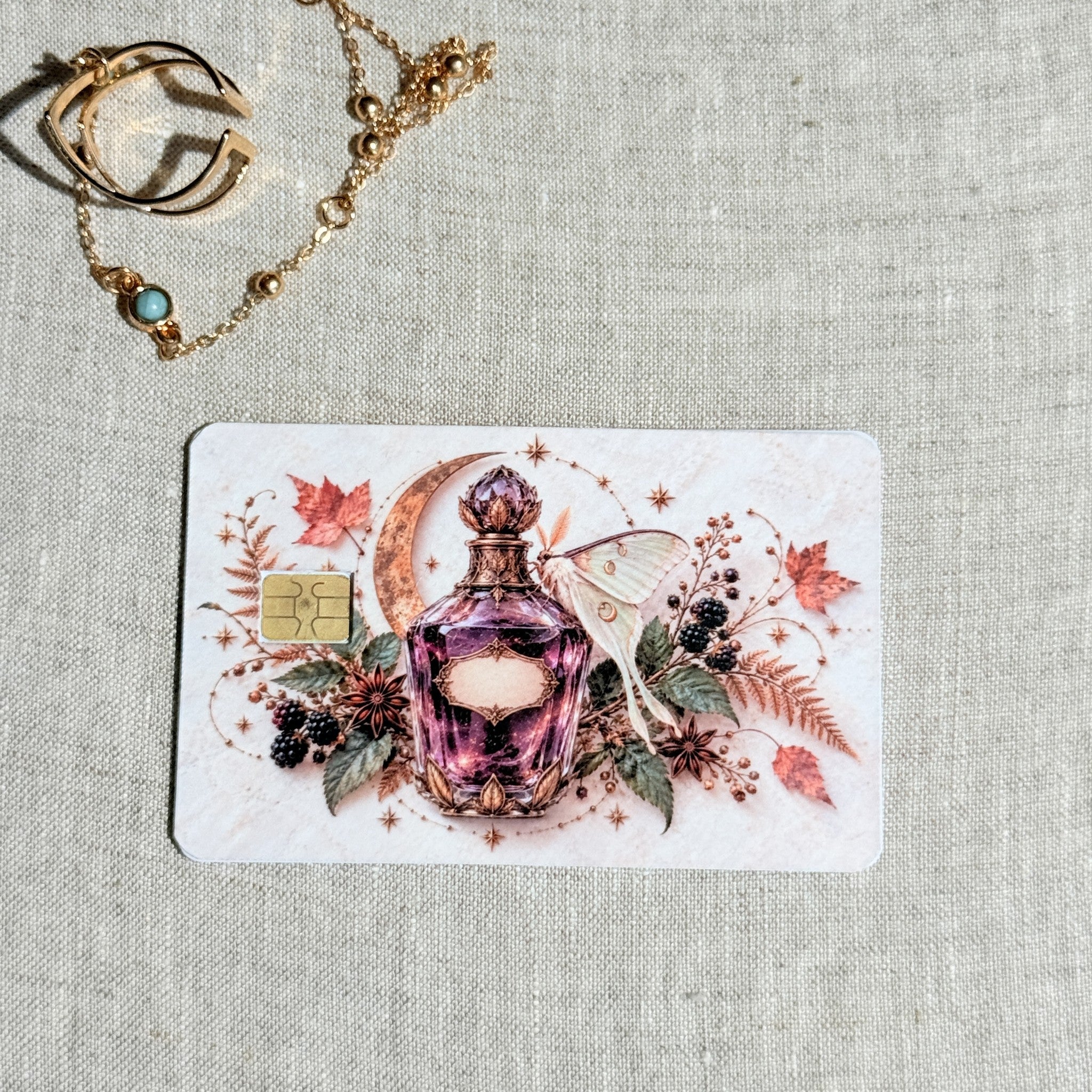 Autumn potion card skin on a debit card, rose pink apothecary bottle with a luna moth and moon