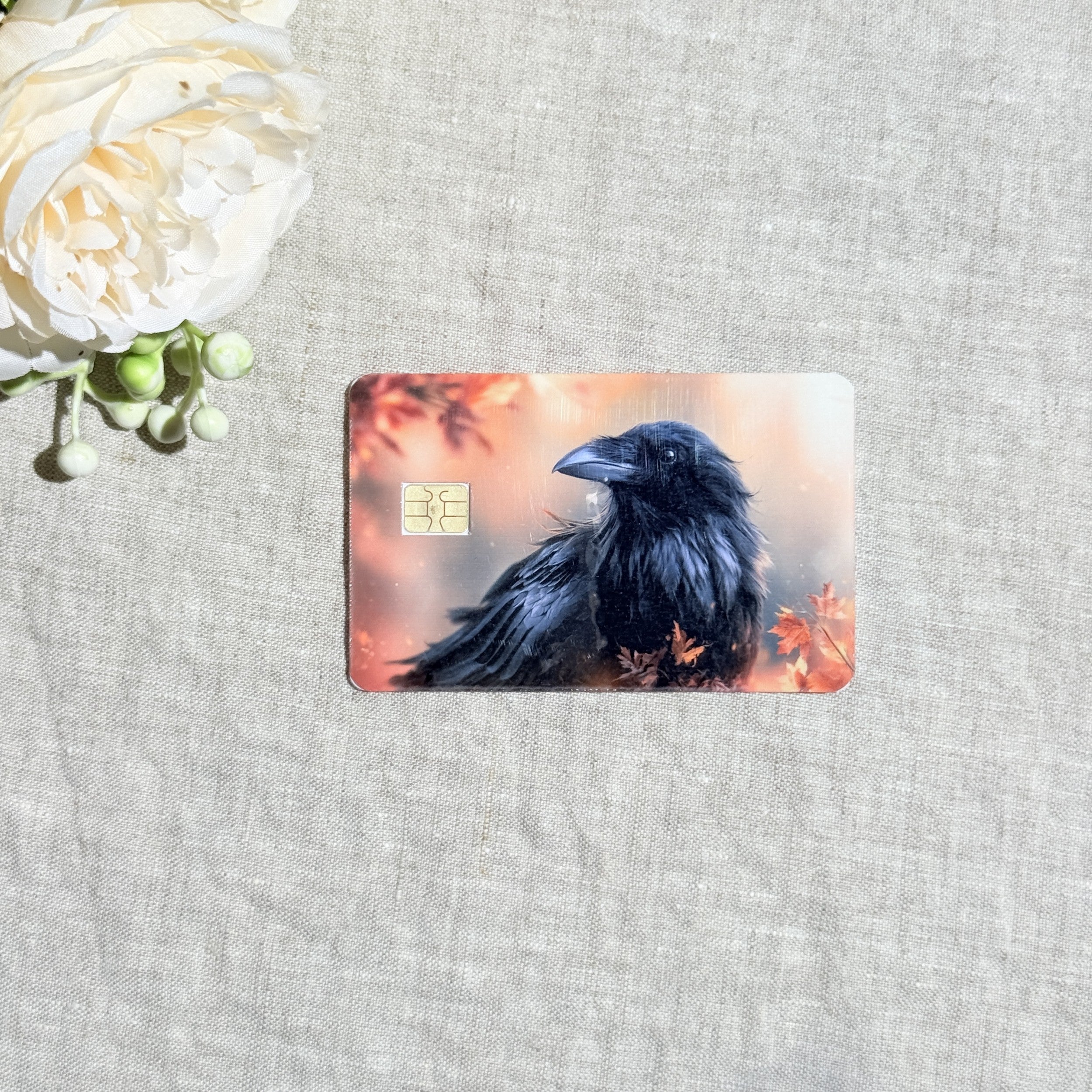 Autumn raven card skin with a black raven among orange fall leaves on a debit card by The Sticker Era