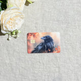 Black raven fall leaves card skin flat lay on cream linen by The Sticker Era