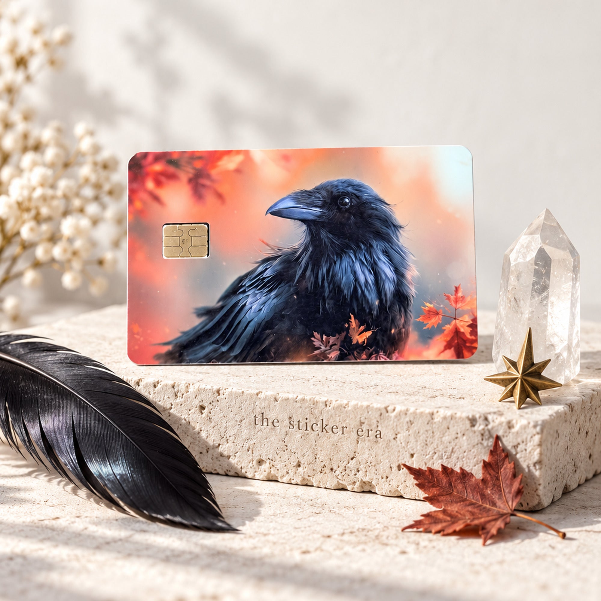 Autumn raven credit card sticker standing beside a black feather and quartz crystal by The Sticker Era