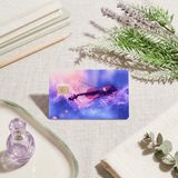 Purple cosmic violin card skin on linen with rosemary, a pencil and glass bottle BY THE STICKER ERA