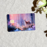 Enchanted fawn card skin with a baby deer in a glowing pink and purple forest on a debit card by The Sticker Era