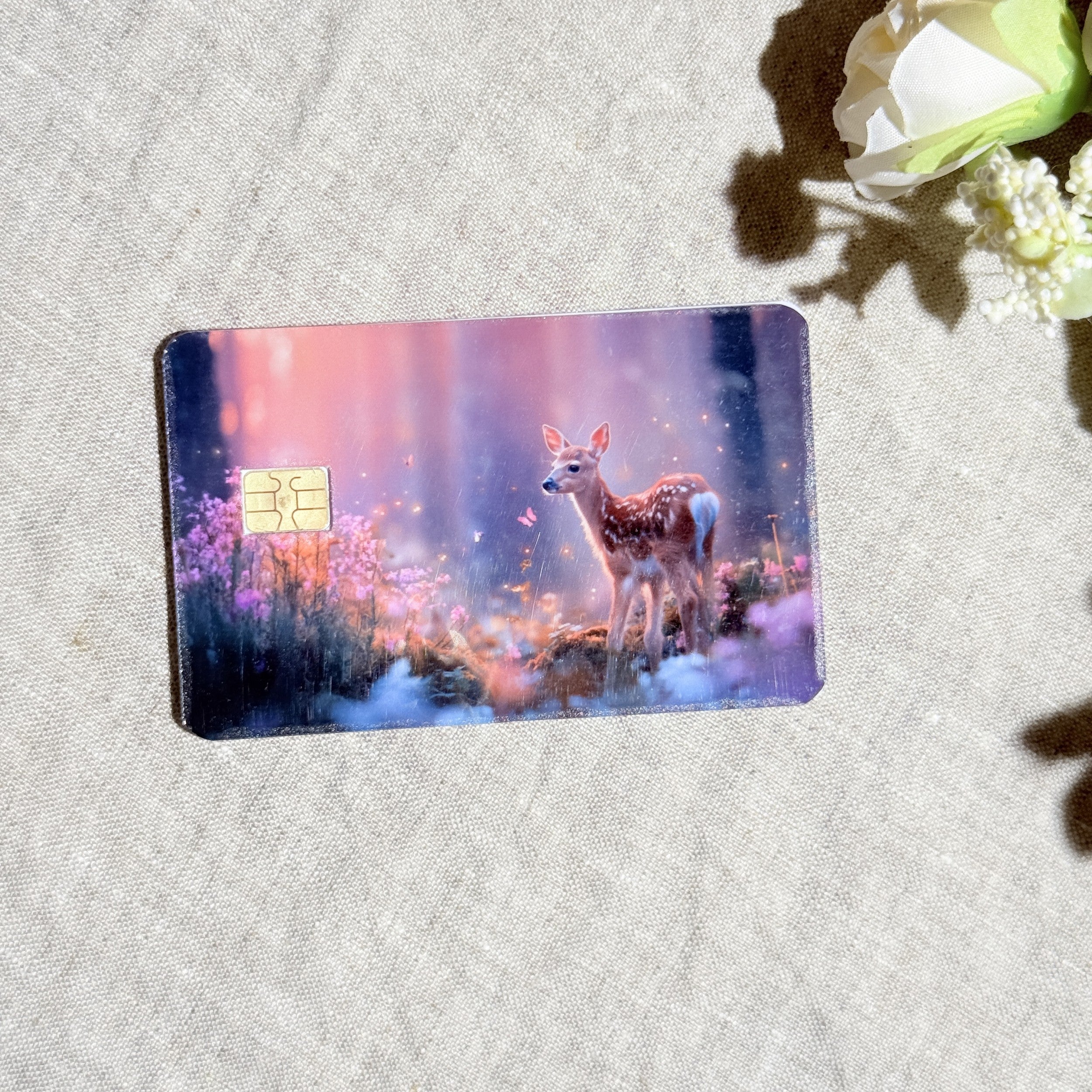 Enchanted fawn card skin with a baby deer in a glowing pink and purple forest on a debit card by The Sticker Era