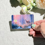 Hand holding the enchanted fawn debit card skin in sunlight by The Sticker Era