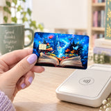 Hand holding the enchanted storybook card skin at a card reader beside a Good Books Brighter Days mug by The Sticker Era