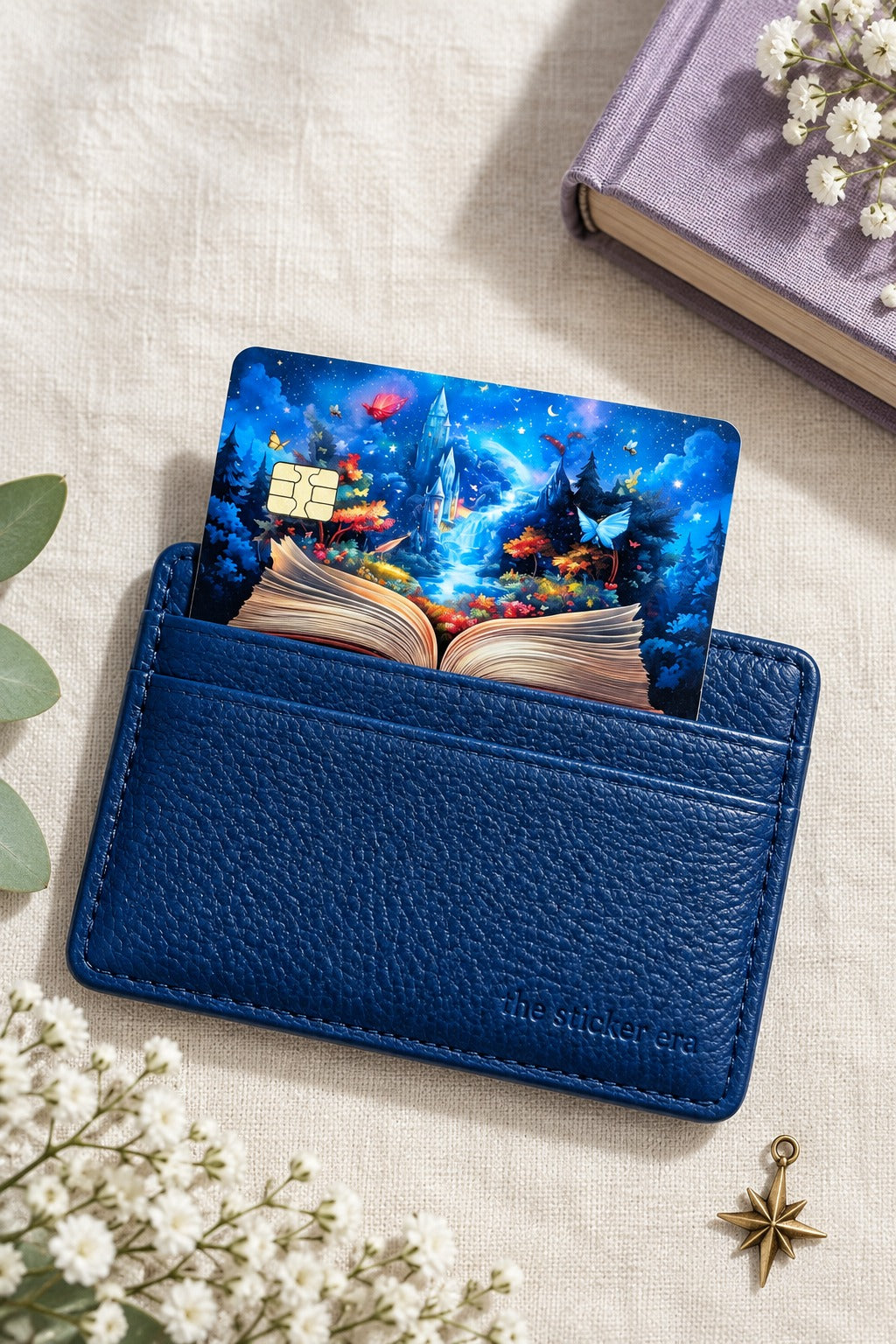 Enchanted storybook card skin tucked into a navy leather cardholder with baby's breath and a star charm by The Sticker Era