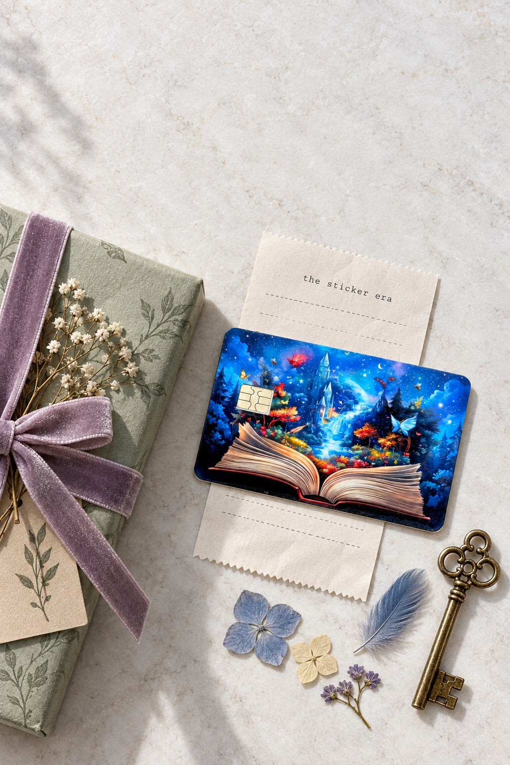 Enchanted storybook card skin beside a sage gift box with a velvet ribbon, pressed flowers and a brass key by The Sticker Era