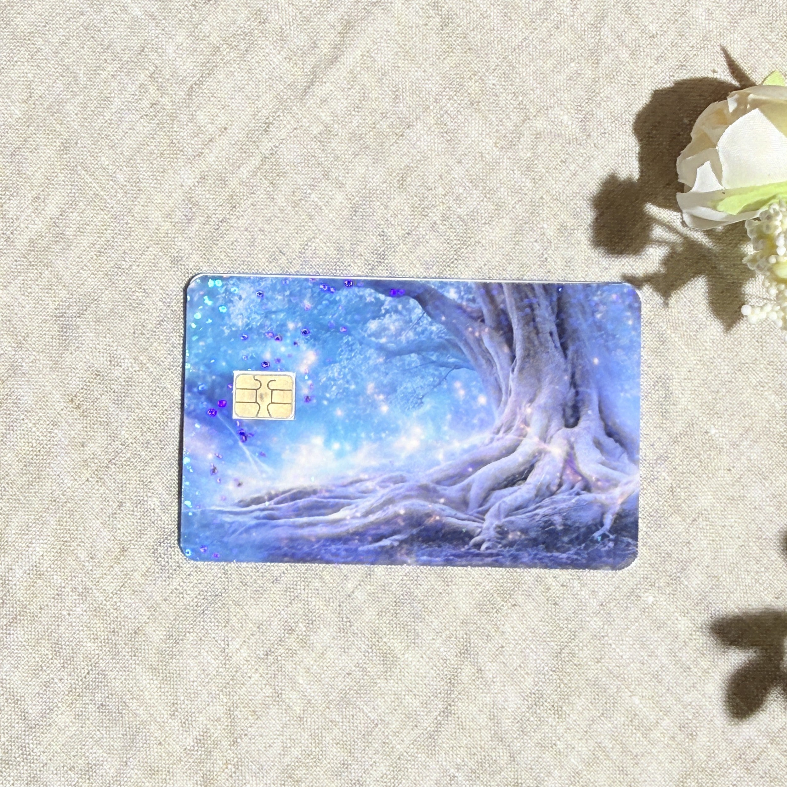 Enchanted tree card skin with a glowing blue fairy forest and twisted roots on a debit card by The Sticker Era