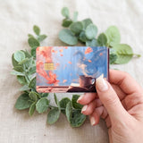 Hand holding the autumn dragon and coffee card skin with eucalyptus by The Sticker Era