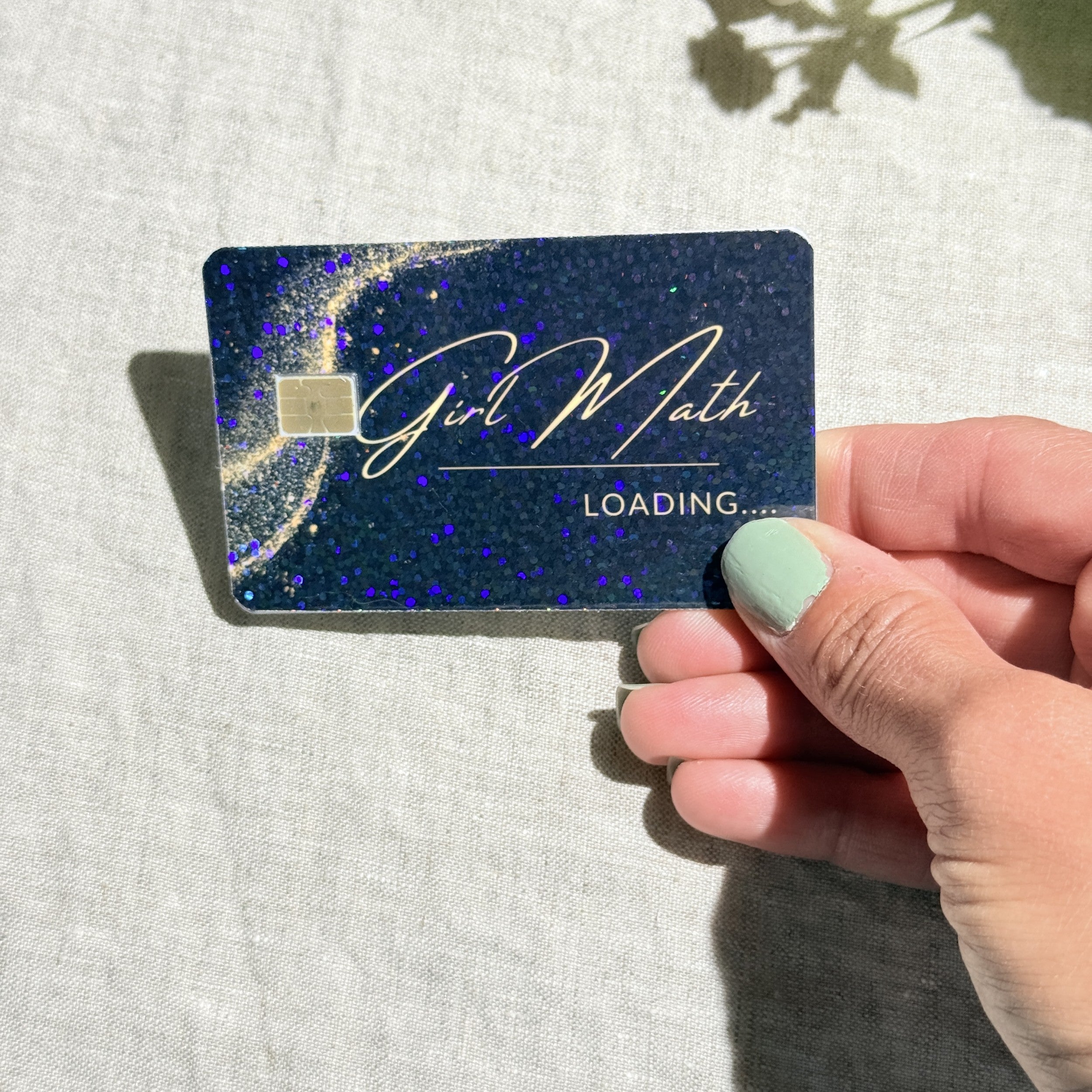 Hand holding the Girl Math debit card skin in sunlight by The Sticker Era