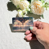 Hand holding the golden dragon debit card skin in sunlight by The Sticker Era
