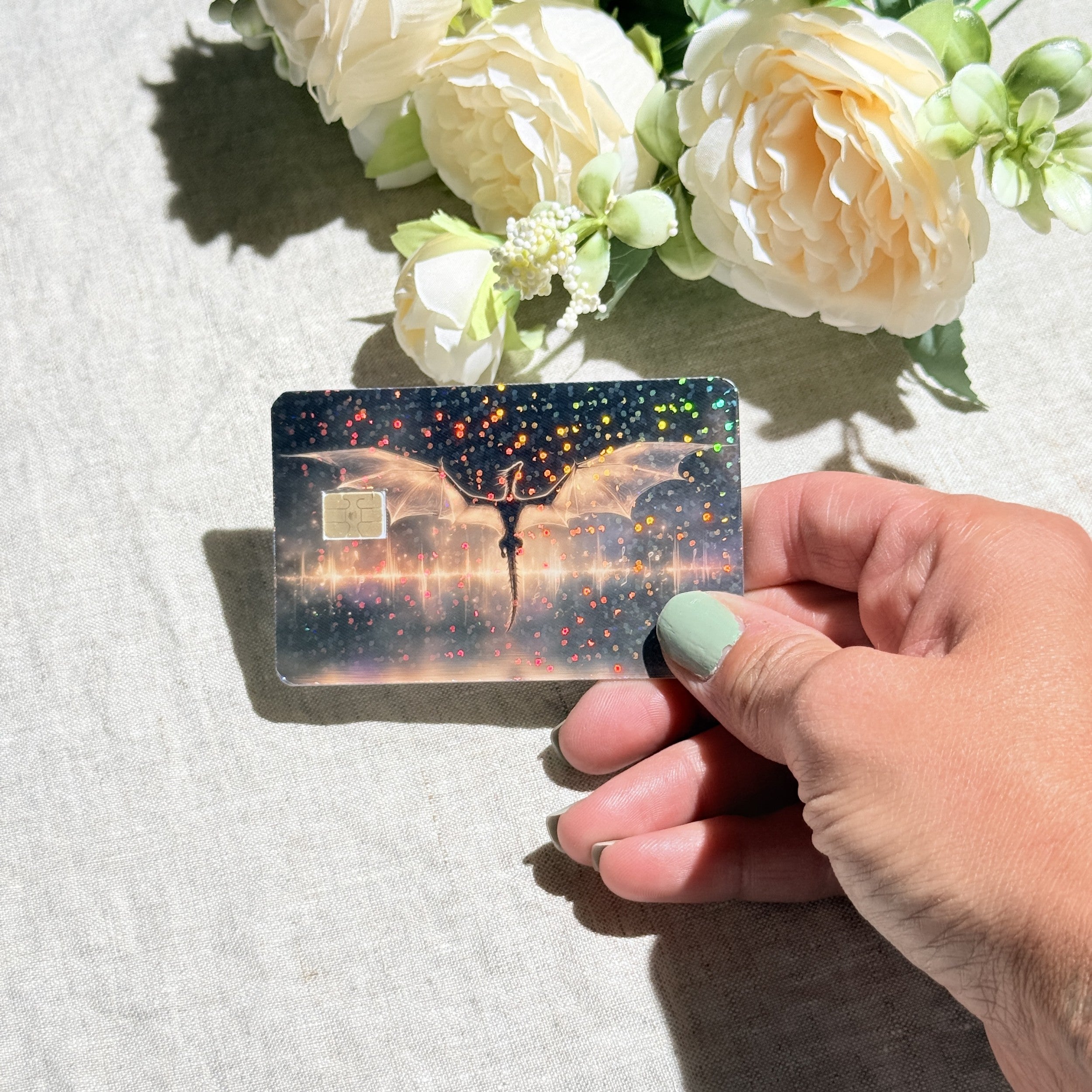 Hand holding the golden dragon debit card skin in sunlight by The Sticker Era