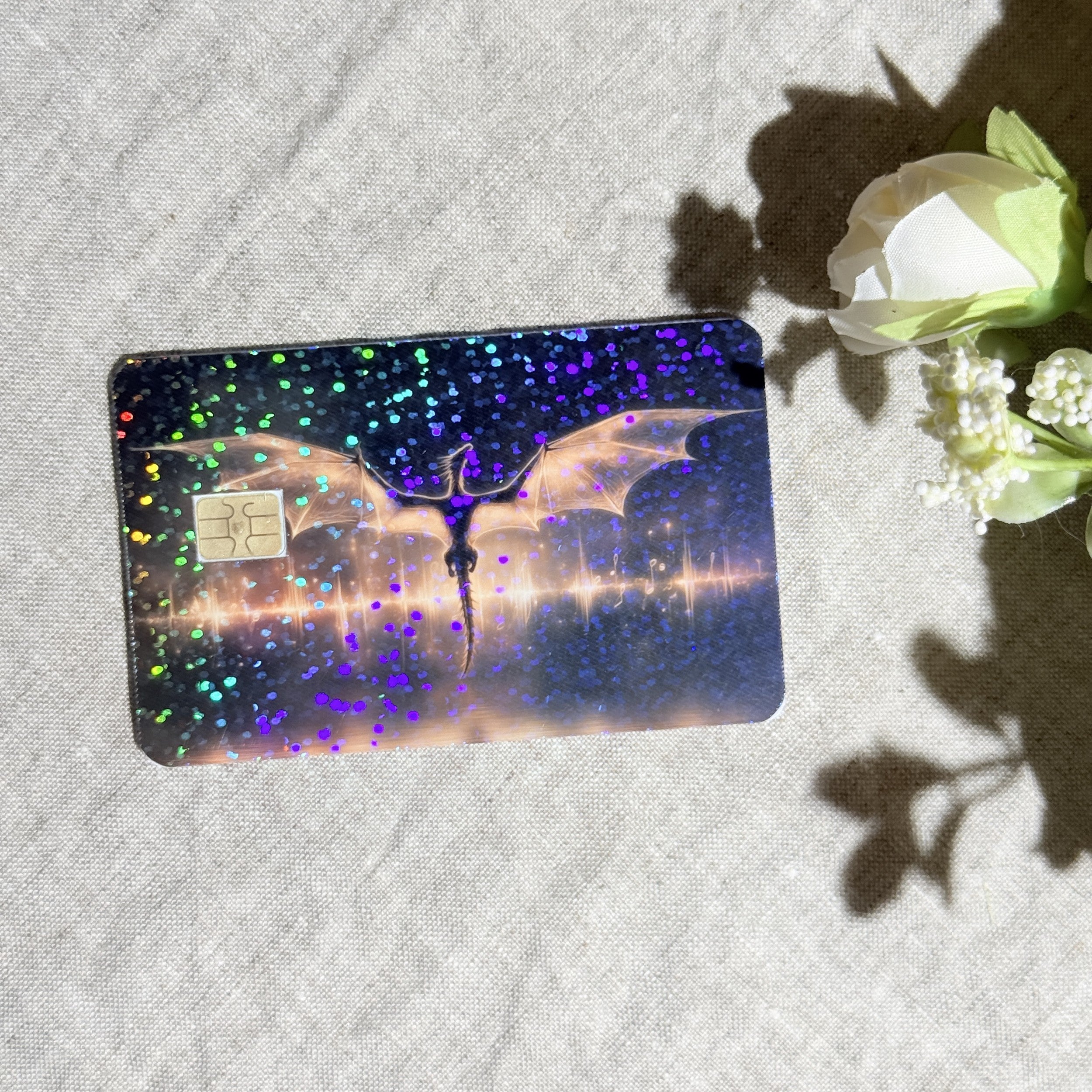 Dragon over the lake card skin flat lay on cream linen with holographic sparkle by The Sticker Era