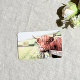 Highland cow at the fence card skin flat lay on cream linen by The Sticker Era