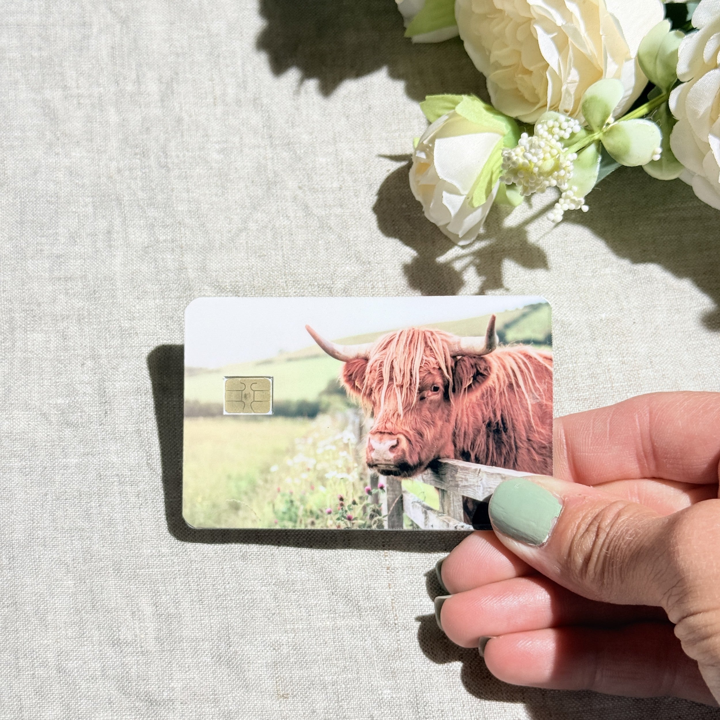 Close-up of the fluffy highland cow and wildflowers on the card skin by The Sticker Era
