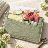 Highland cow credit card sticker tucked into a sage green card wallet with clover by The Sticker Era
