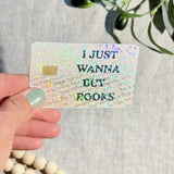 Hand holding the I Just Wanna Buy Books sparkle card skin in sunlight by The Sticker Era