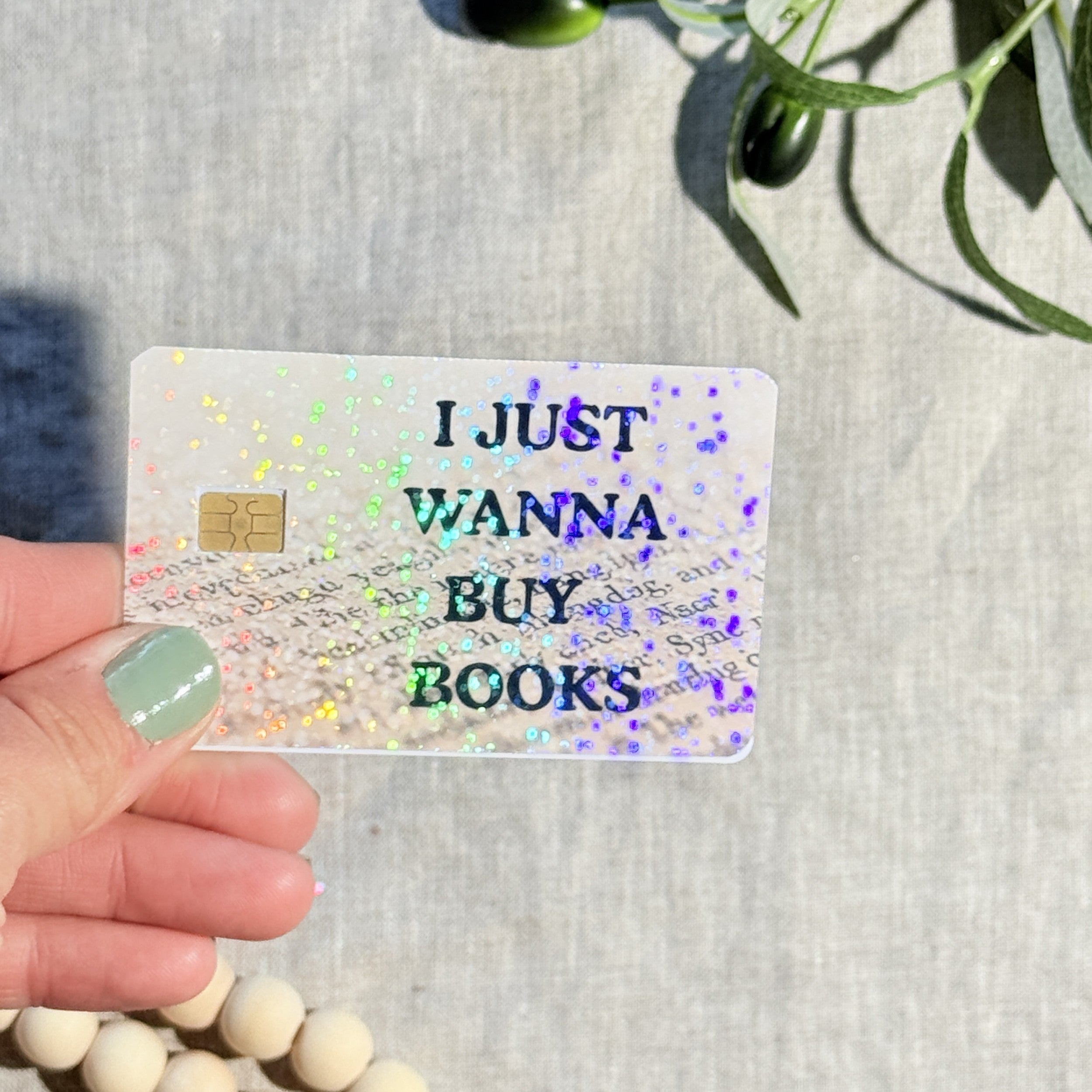 Funny book lover debit card skin held up showing rainbow sparkle by The Sticker Era