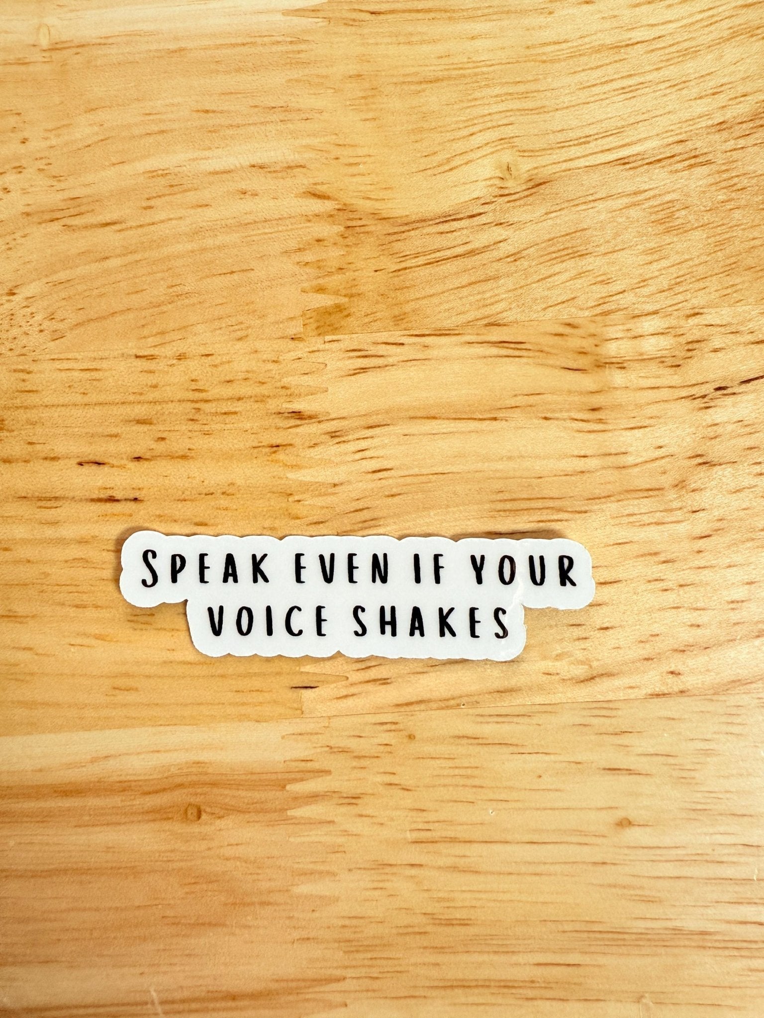 Speak Even If Your Voice Shakes" vinyl sticker on a wooden surface