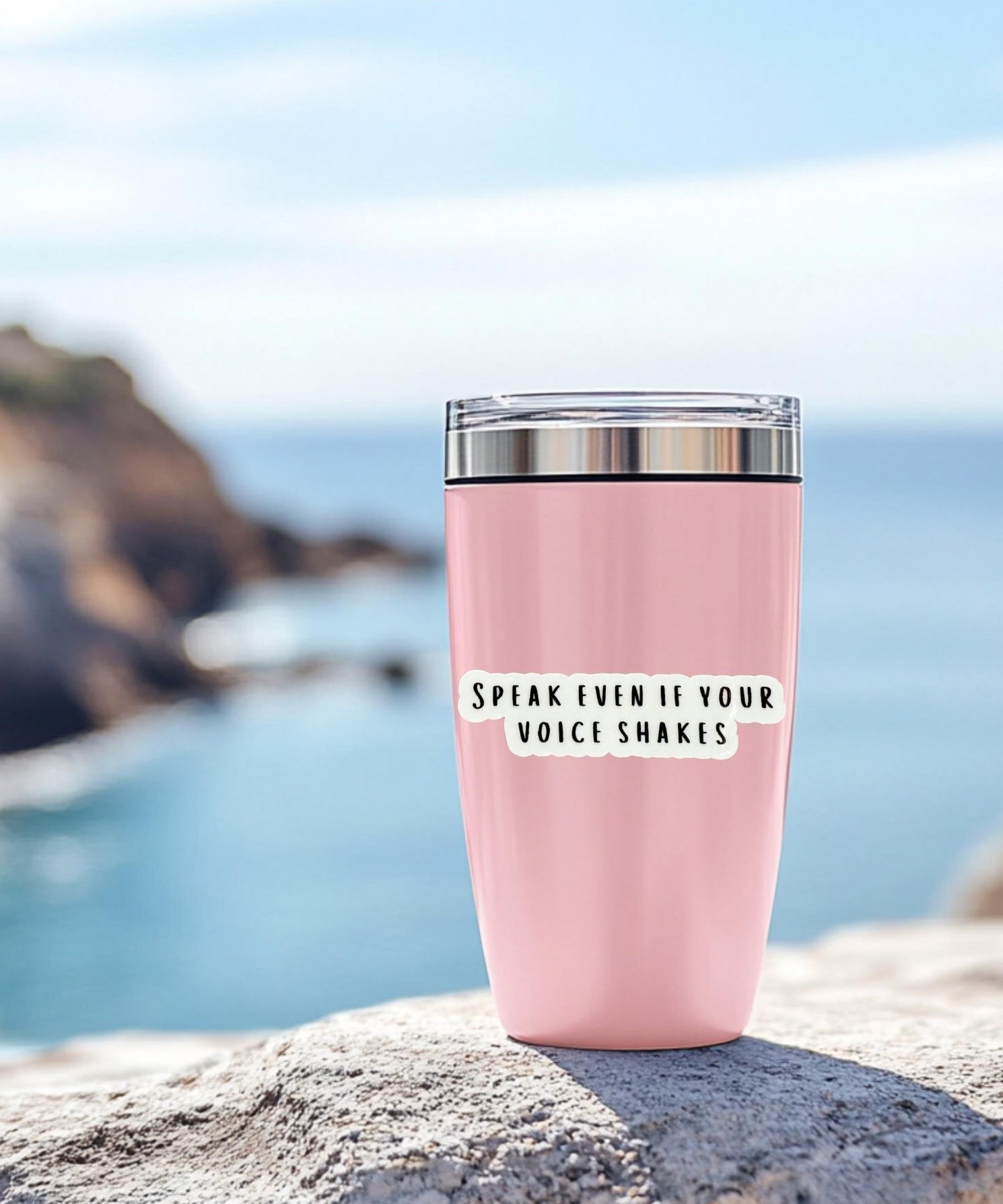 Speak Even If Your Voice Shakes" sticker on a pink tumbler by the ocean