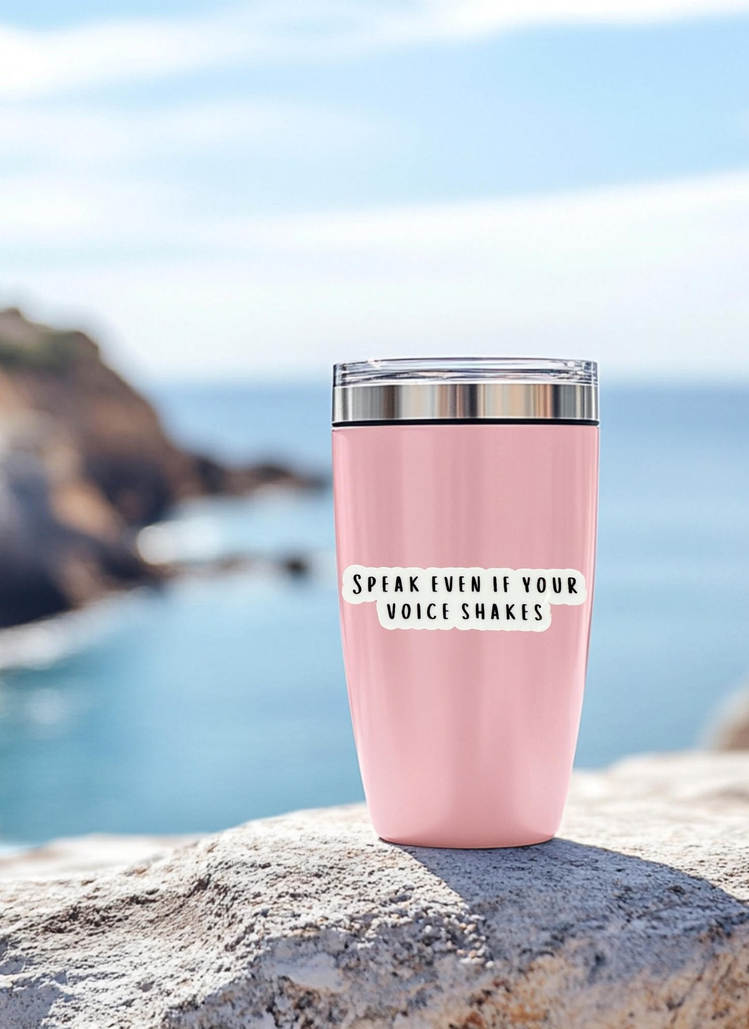 Speak Even If Your Voice Shakes" sticker on a pink tumbler by the ocean