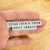 Close-up of the "Speak Even If Your Voice Shakes" sticker held near a person's lips