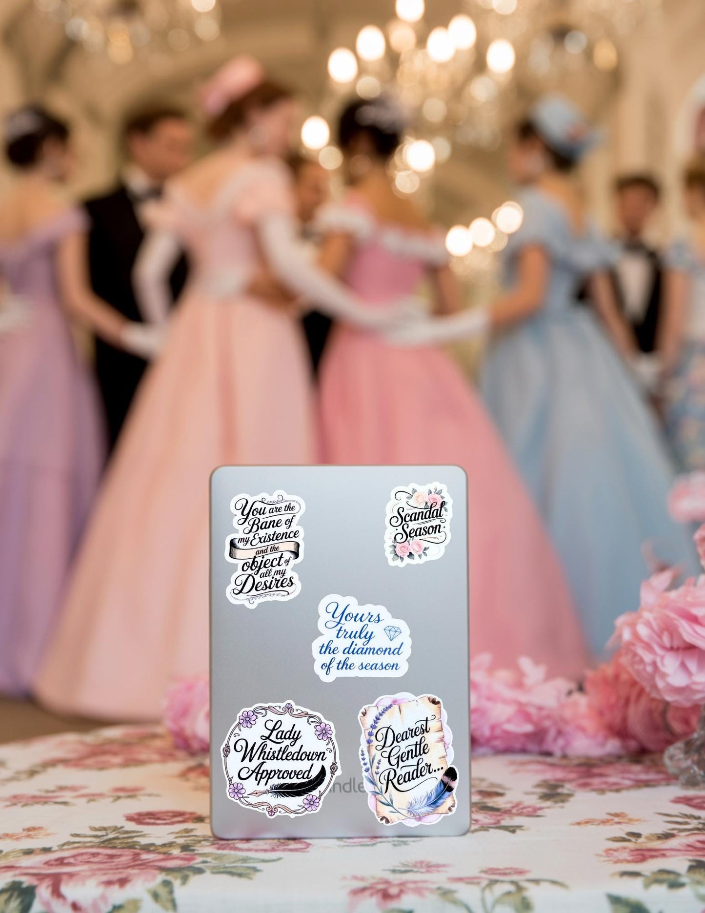 A set of Bridgerton-inspired vinyl stickers featuring romantic quotes and elegant script designs. Displayed on a light blue journal with pink floral decor in the background. Perfect for fans of period romance and bookish aesthetics.