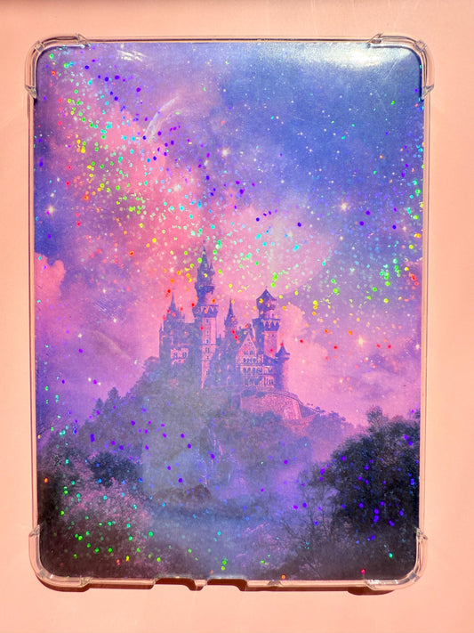 A Kindle insert featuring a misty purple fantasy castle sitting on a hill beneath a dreamy galaxy sky, with holographic rainbow sparkles scattered across the image. The aesthetic is magical and ethereal, perfect for romantasy and fairytale lovers. Photographed on a pink background.